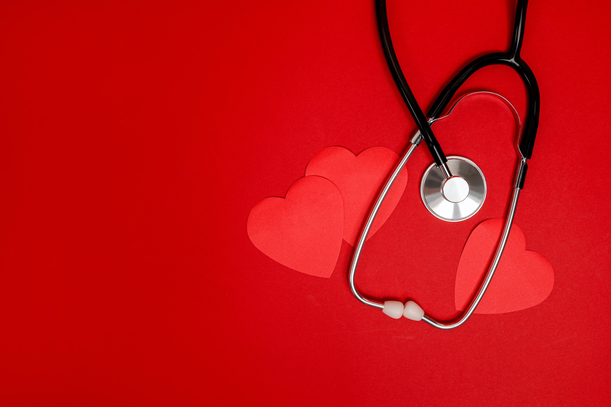Red hearts with stethoscope on red background, heart health, health insurance concept
