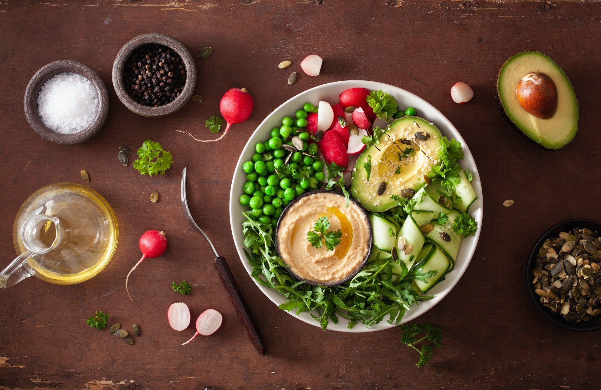 healthy vegan lunch bowl with avocaco cucumber hummus peas radis