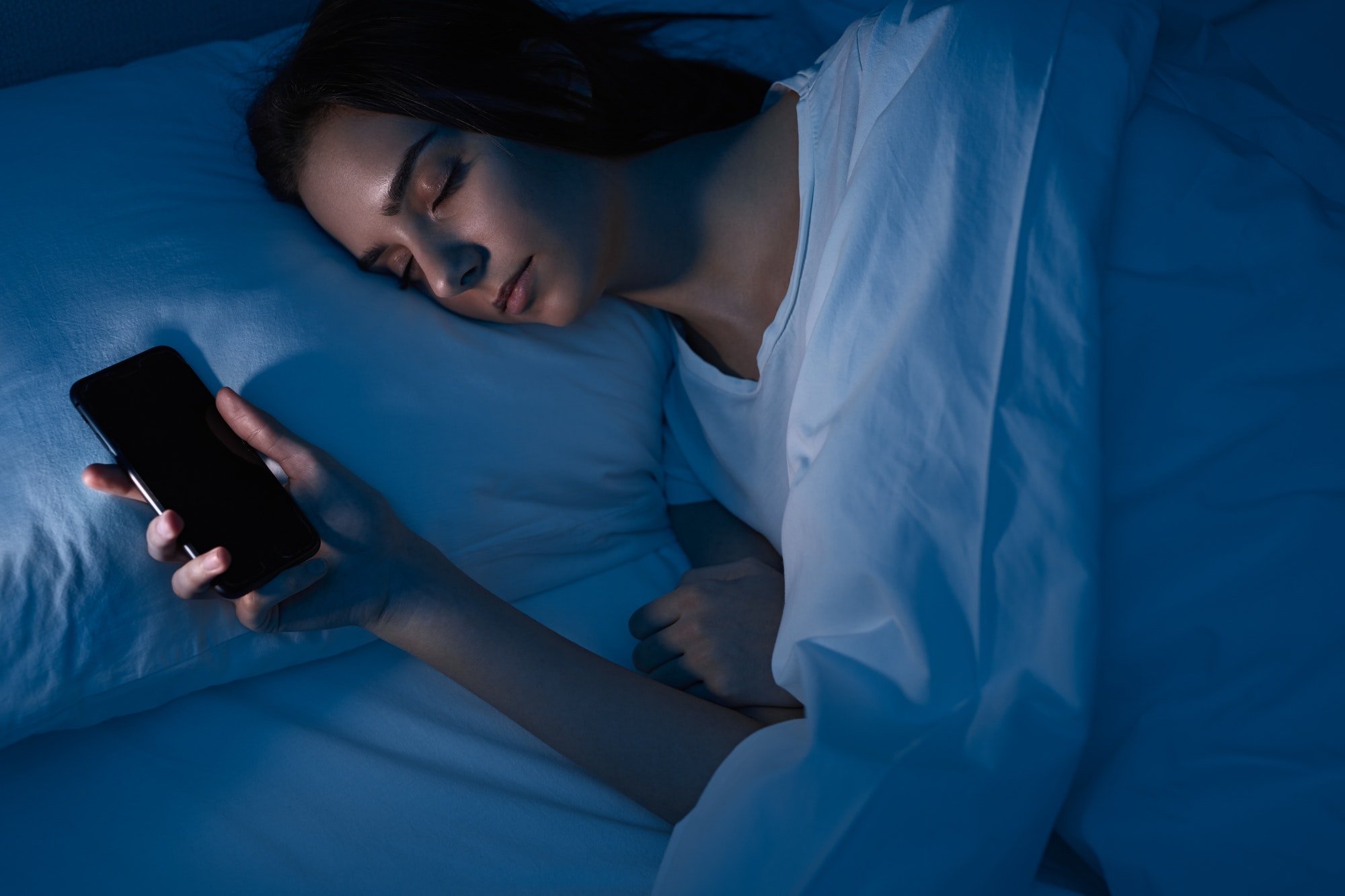 Woman sleeping with smartphone in bed