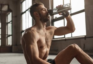 Muscular man drinking water after workout