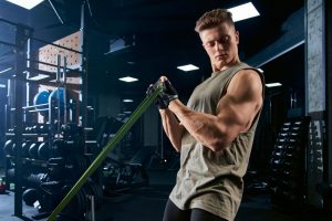 Bodybuilder training biceps with resistance band