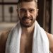 Crop smiling sportsman with towel after workout in gym