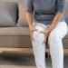 Elderly woman massaging the knee easing the aches. Joint pain concept.