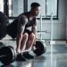 focused muscular sportsman training with barbell at gym