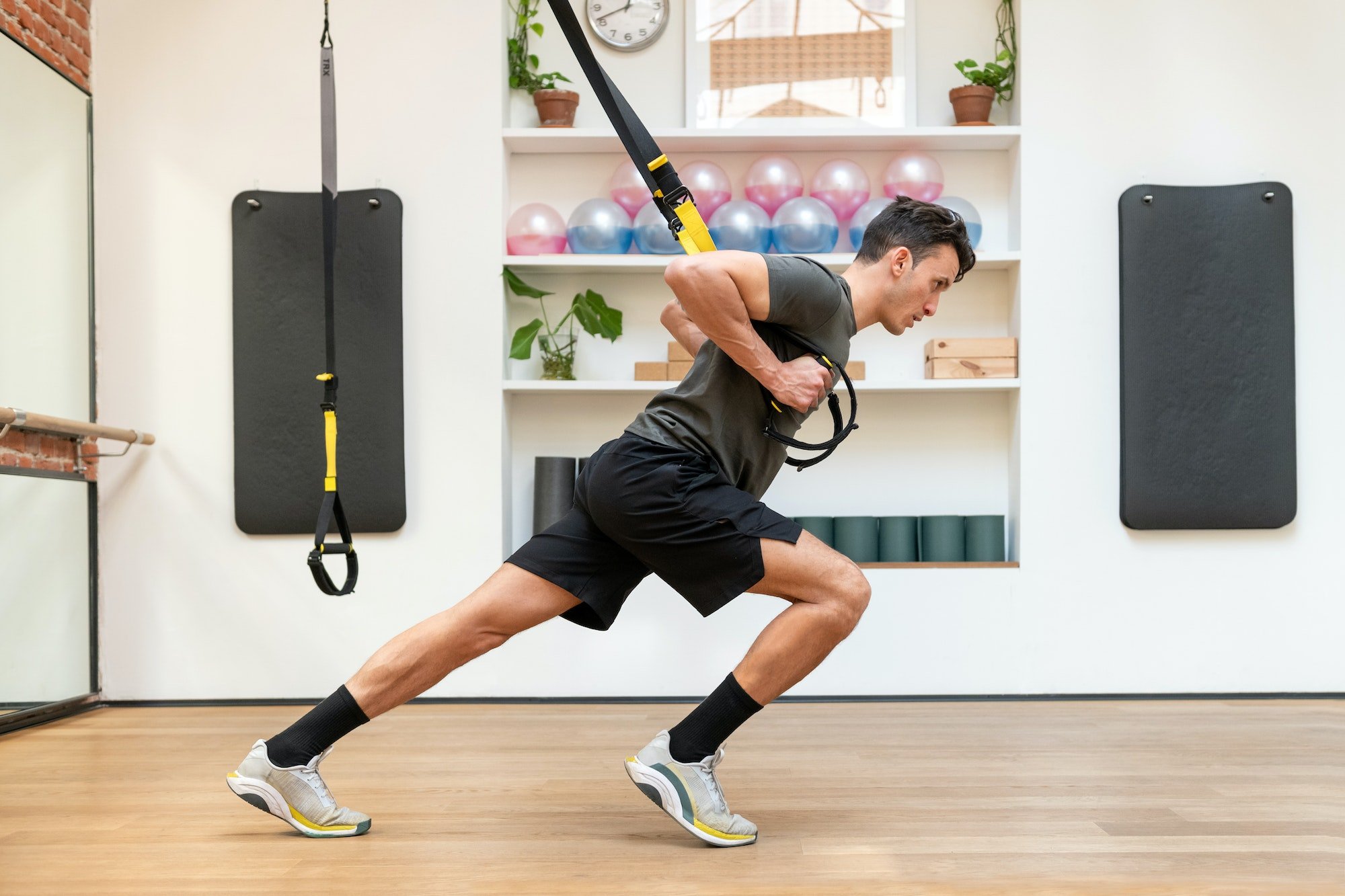 Muscular sportsman exercising on TRX straps in gym