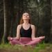 Redhead young woman meditating in a forest.
