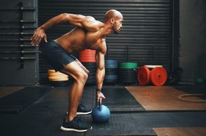 Shot of a muscular young man exercising with a kettlebell in a gym