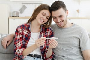 Young couple looks at positive results of pregnancy test planning future family