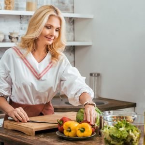 blonde adult woman preparing salad for dinner at home