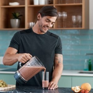 Cropped shot of a handsome young man making smoothies in his kitchen at home