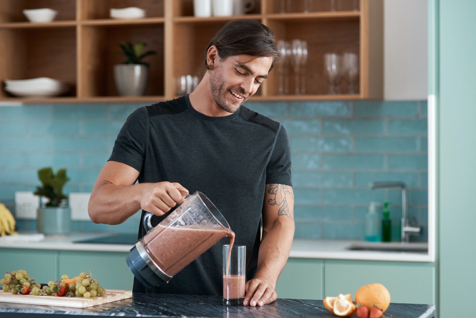 Cropped shot of a handsome young man making smoothies in his kitchen at home