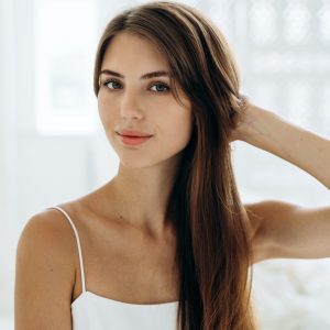 Portrait of adorable woman with healthy skin sitting in front of the camera with calm expression