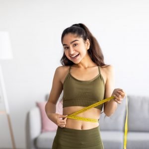 Successful weight loss. Slim Indian woman measuring waist with tape, satisfied with slimming program