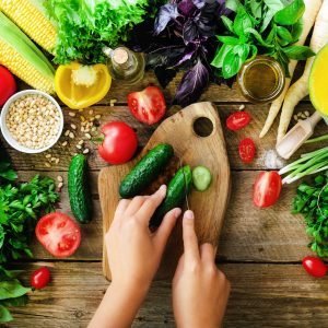 Woman hands cutting vegetables on wooden background. Vegetables cooking ingredients, top view, copy