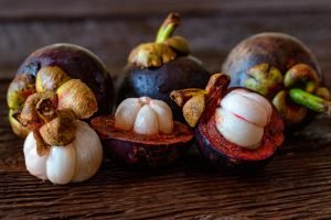 Freshly peeled mangosteen fruit on wooden table close up