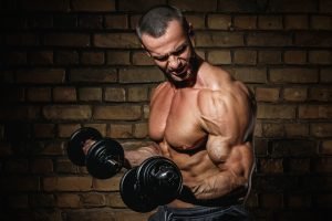 Bodybuilder doing exercises for biceps with a dumbbells