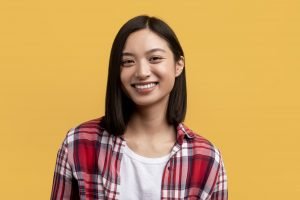 Happy person. Portrait of young asian lady with beautiful smile, looking at camera, posing in studio