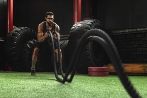 Man is making battle rope exercises during his cross training workout