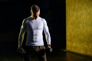 Man training in the gym using dumbbells