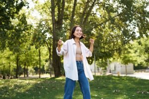 Portrait of happy girl dancing and looking happy, posing in park, enjoying herself, walking alone