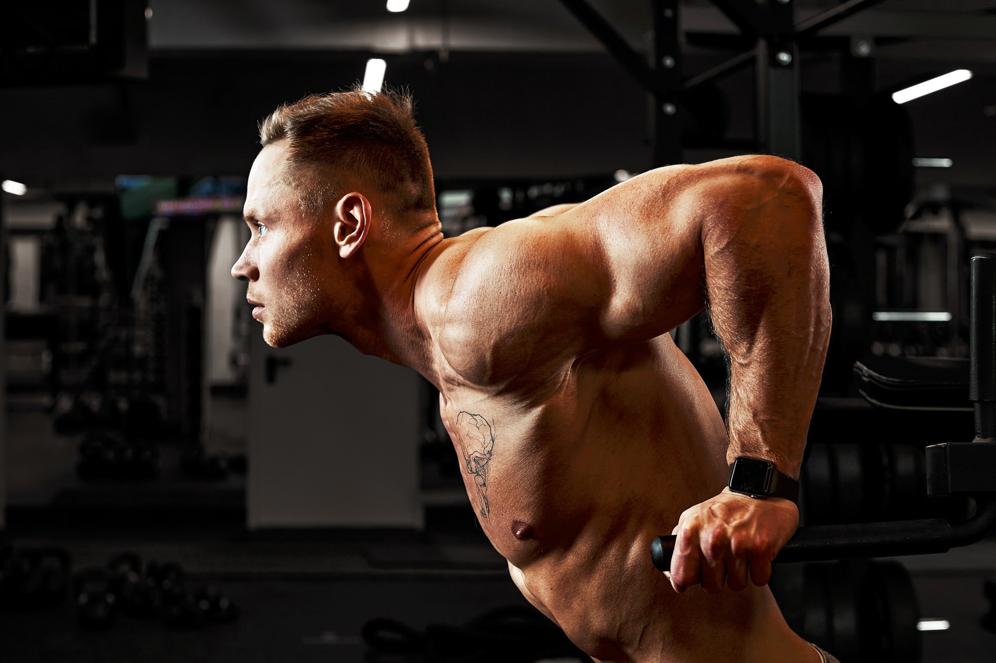Man an athlete is engaged in a gym, doing an exercise on the muscles of the arms biceps black