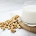 Plant based milk with heap of cashew nuts on wooden board.