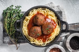Vegan tomato pasta with plant based Meatballs in a skillet. White background. Top view