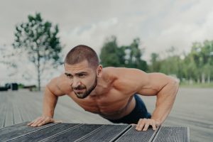 active bearded European man does exercises for shouldrs, chest and bicep