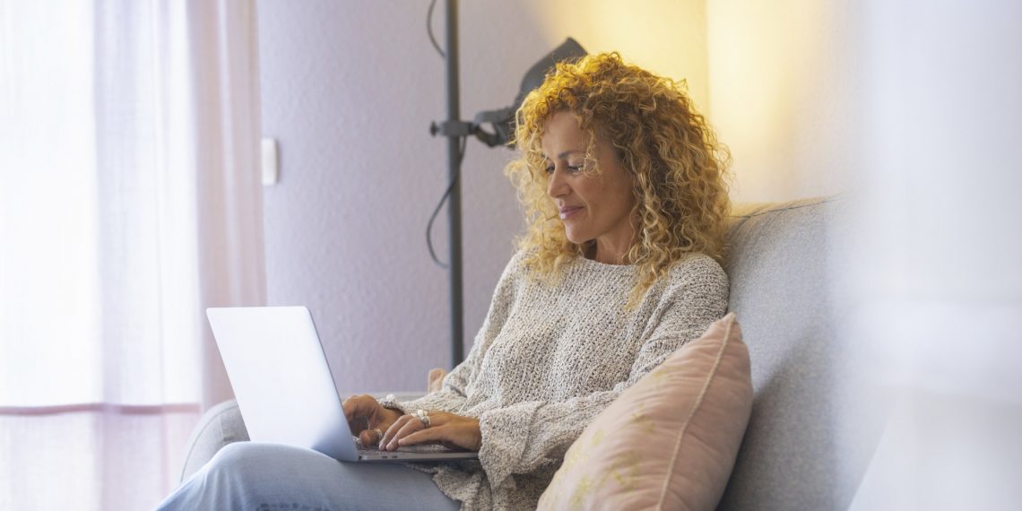 Relaxed and happy adult attractive woman working at home with laptop computer