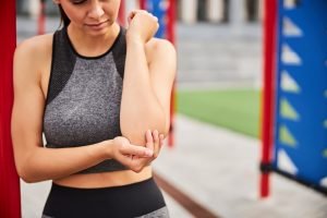 Young woman hurt elbow during workout outdoors