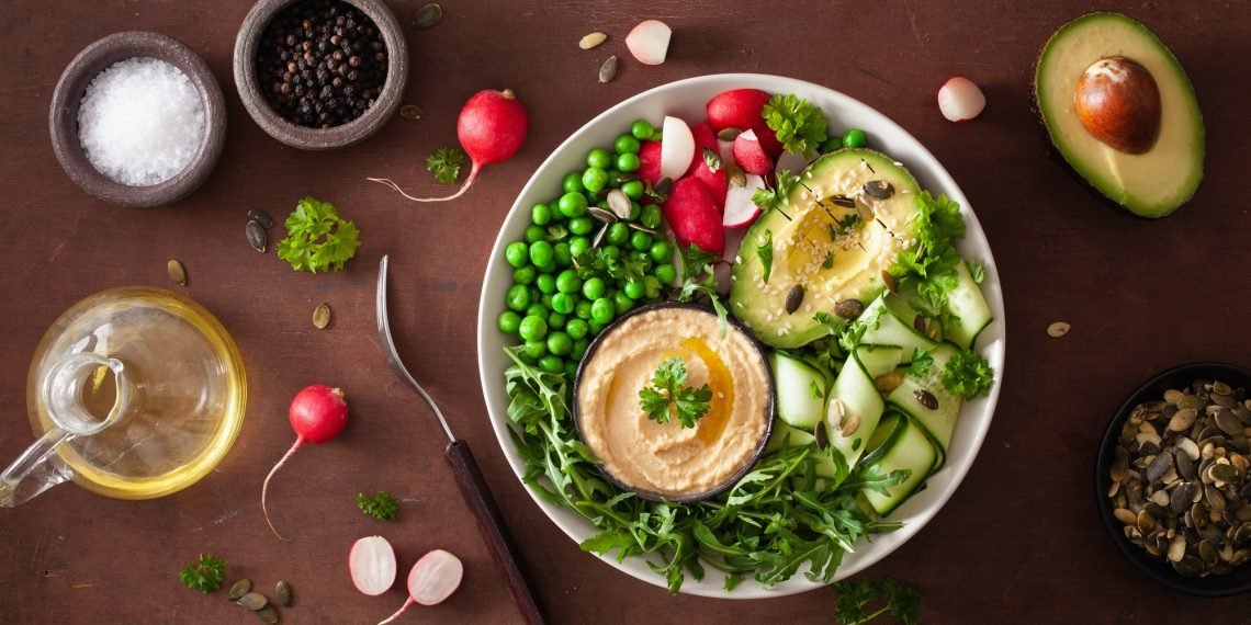 healthy vegan lunch bowl with avocaco cucumber hummus peas radis