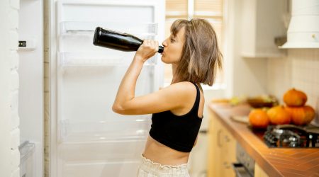 Drunk woman ashwagandha drink some alcohol near fridge at home