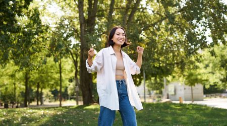 Portrait of happy girl dancing and looking happy, posing in park, enjoying herself, walking alone